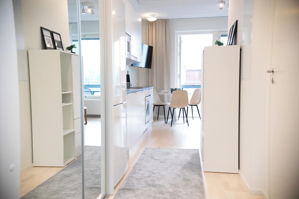 A modern kitchen with white cabinets, a built-in oven, and a flat-screen TV.