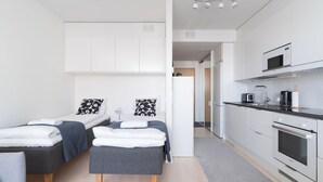 A modern, compact living space with a kitchenette, two beds with matching decor, and a clean, minimalist design. - Rahulihomes Jyväskylä (Jyväskylä)
