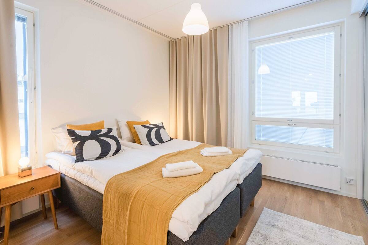 A bedroom with a bed, bedside table, and a window with blinds.