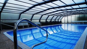 Une piscine intérieure dotée d’un toit incurvé et d’une eau d’un bleu cristallin.