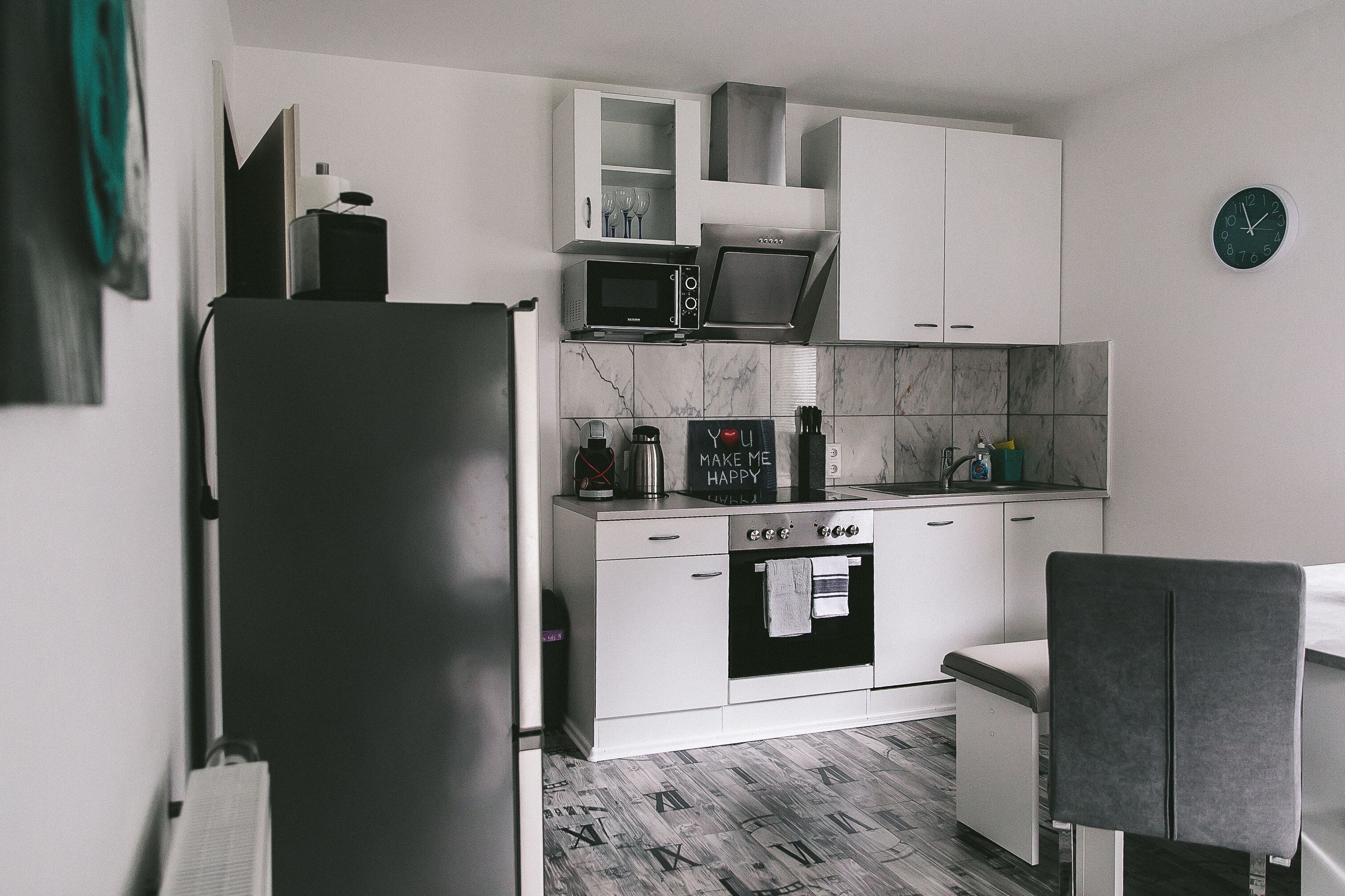 A compact kitchen with white cabinetry, a microwave, a coffee maker, and a small oven.