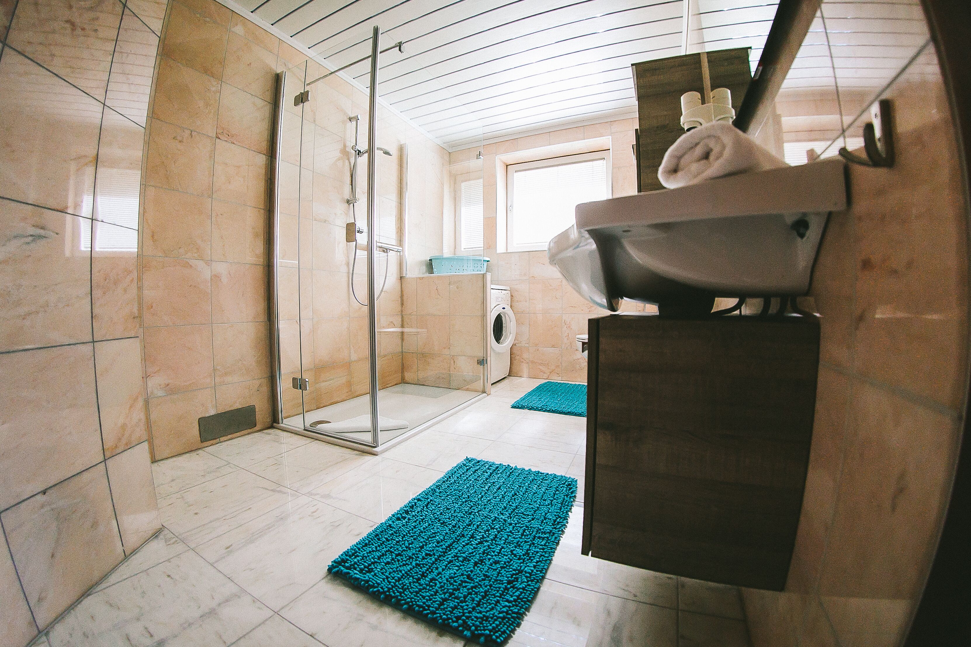 A modern bathroom with a glass shower enclosure, a sink, and a towel rack.