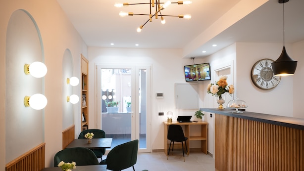 A modern hotel lobby with a reception desk, seating area, and a large clock on the wall. - Incanto B&B (Cefalù)