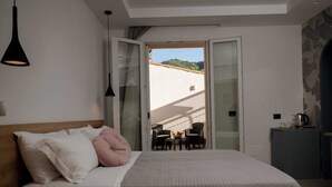 A bedroom with a bed, a nightstand, a desk, a chair, and a balcony with a view. - Incanto B&B (Cefalù)