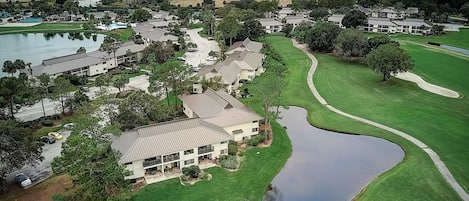 An aerial view of a residential area with houses, a golf course, and a body of water.