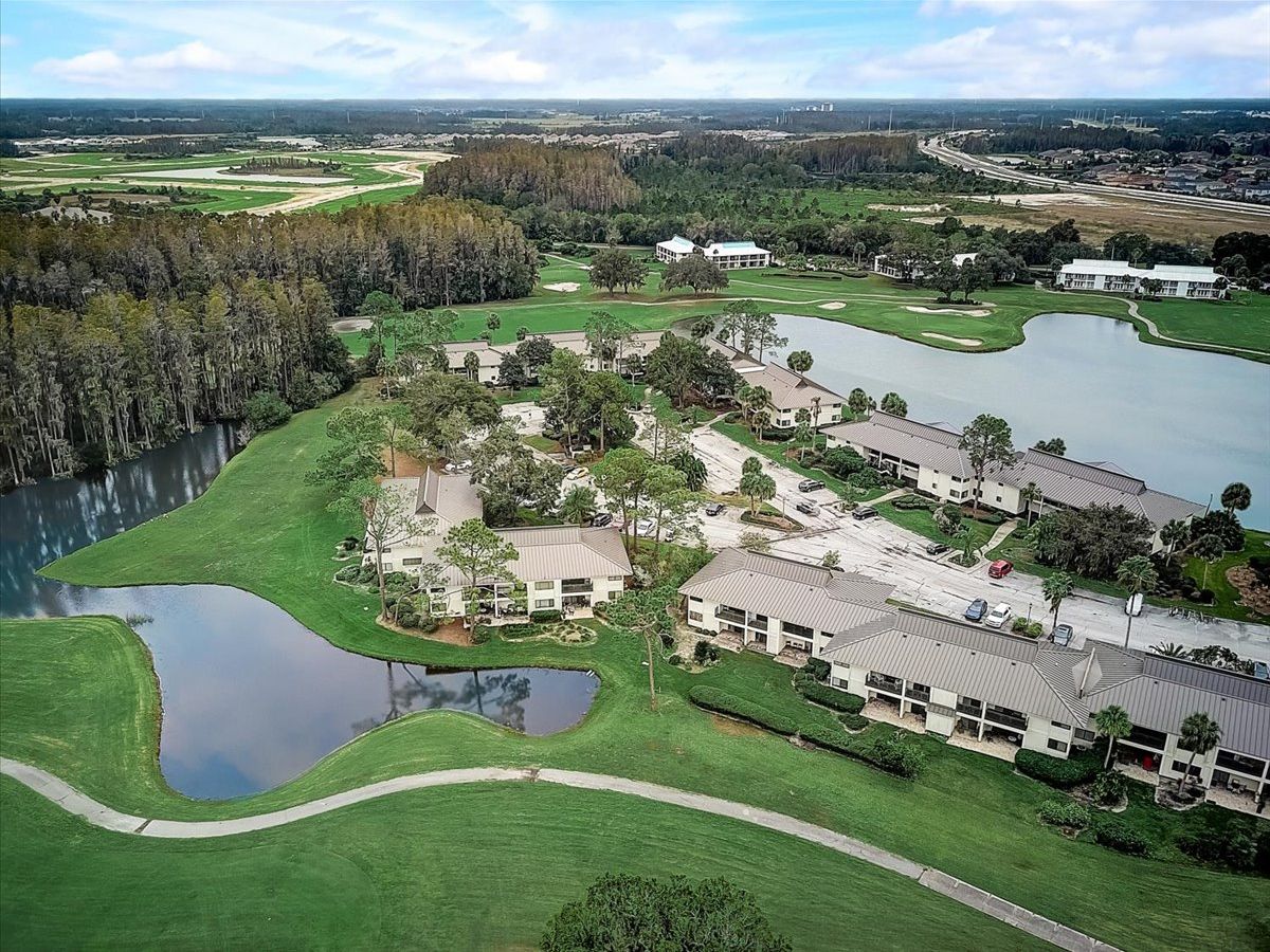 Vista aérea de un campo de golf con un club de campo, varias edificaciones y un lago.