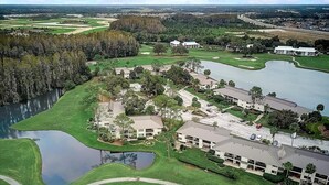 Vista aérea de un campo de golf con un club de campo, varias edificaciones y un lago.