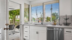 A modern kitchen with white cabinets, a stainless steel dishwasher, and a window with blinds. - Newly Remodeled Home @ the Omni at Rancho Las Palmas in Rancho Mirage! (Rancho Mirage)