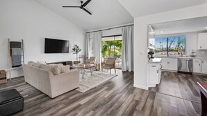 A modern living room with a sofa, TV, and dining area. - Newly Remodeled Home @ the Omni at Rancho Las Palmas in Rancho Mirage! (Rancho Mirage)