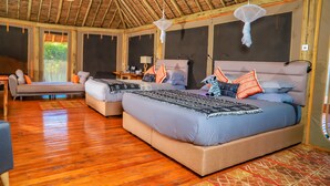 A spacious room with two beds, a sofa, and a wooden floor. - A perfect mix of uncluttered safari simplicity, muted khaki tones. (Talek)