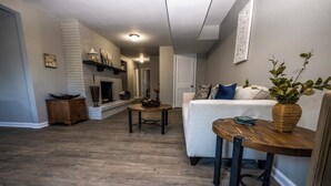 Ein Wohnzimmer mit Kamin, einer Couch, einem Couchtisch und einem Essbereich mit Tisch und Stühlen.