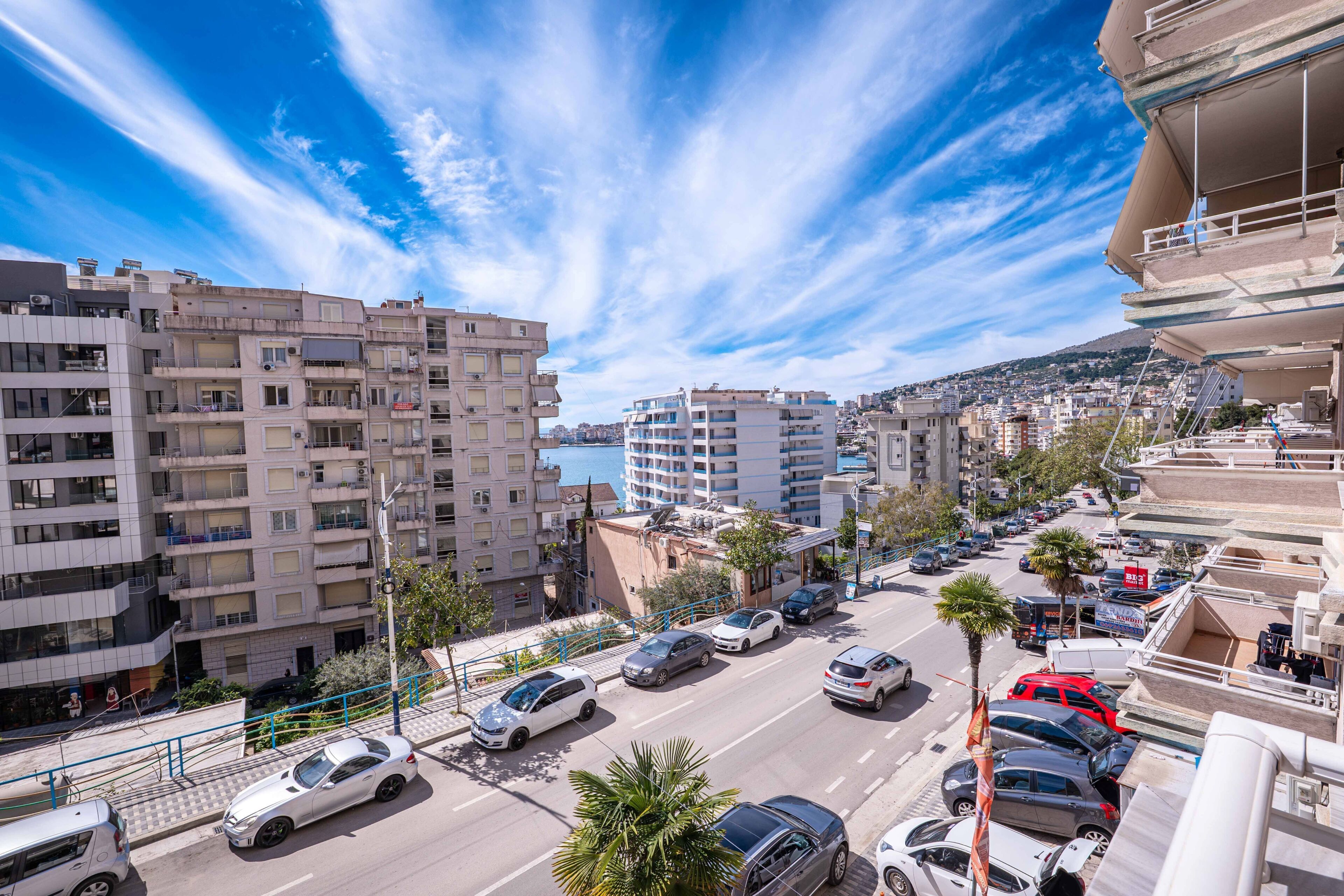 Un edificio a più piani con balconi, un parcheggio con auto e cielo sereno.