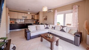 A modern living room with a sectional sofa, a coffee table, and a kitchen in the background.