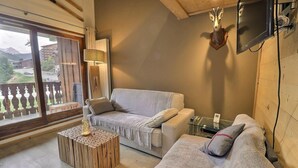 A cozy living room with a sofa, a coffee table, and a mounted television.