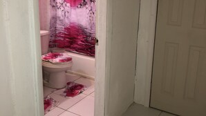 Ein Badezimmer mit Toilette, Badewanne und einer Duschvorhang mit floralem Muster.