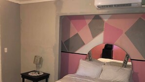 Ein Schlafzimmer mit einem Bett, einem Nachttisch und einer Wand-Klimaanlage.