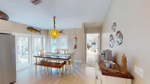 A spacious kitchen with a wooden dining table, white chairs, and a unique chandelier.