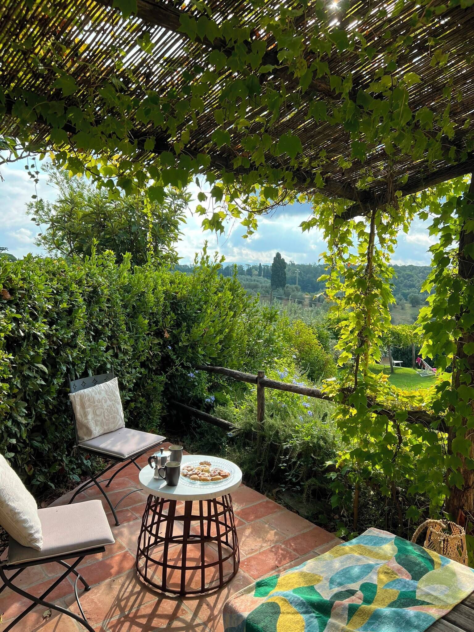 An outdoor patio with a table, chairs, and a view of a landscape.