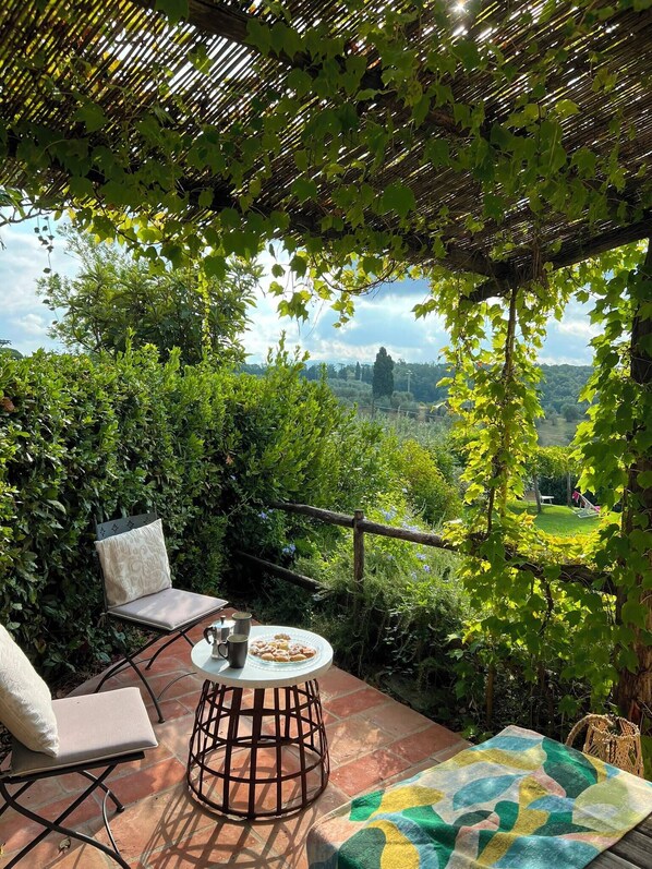 An outdoor patio with a table, chairs, and a view of a landscape.