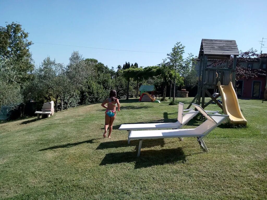 A grassy outdoor area with a slide and a small wooden structure.