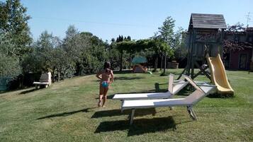 A grassy outdoor area with a slide and a small wooden structure.