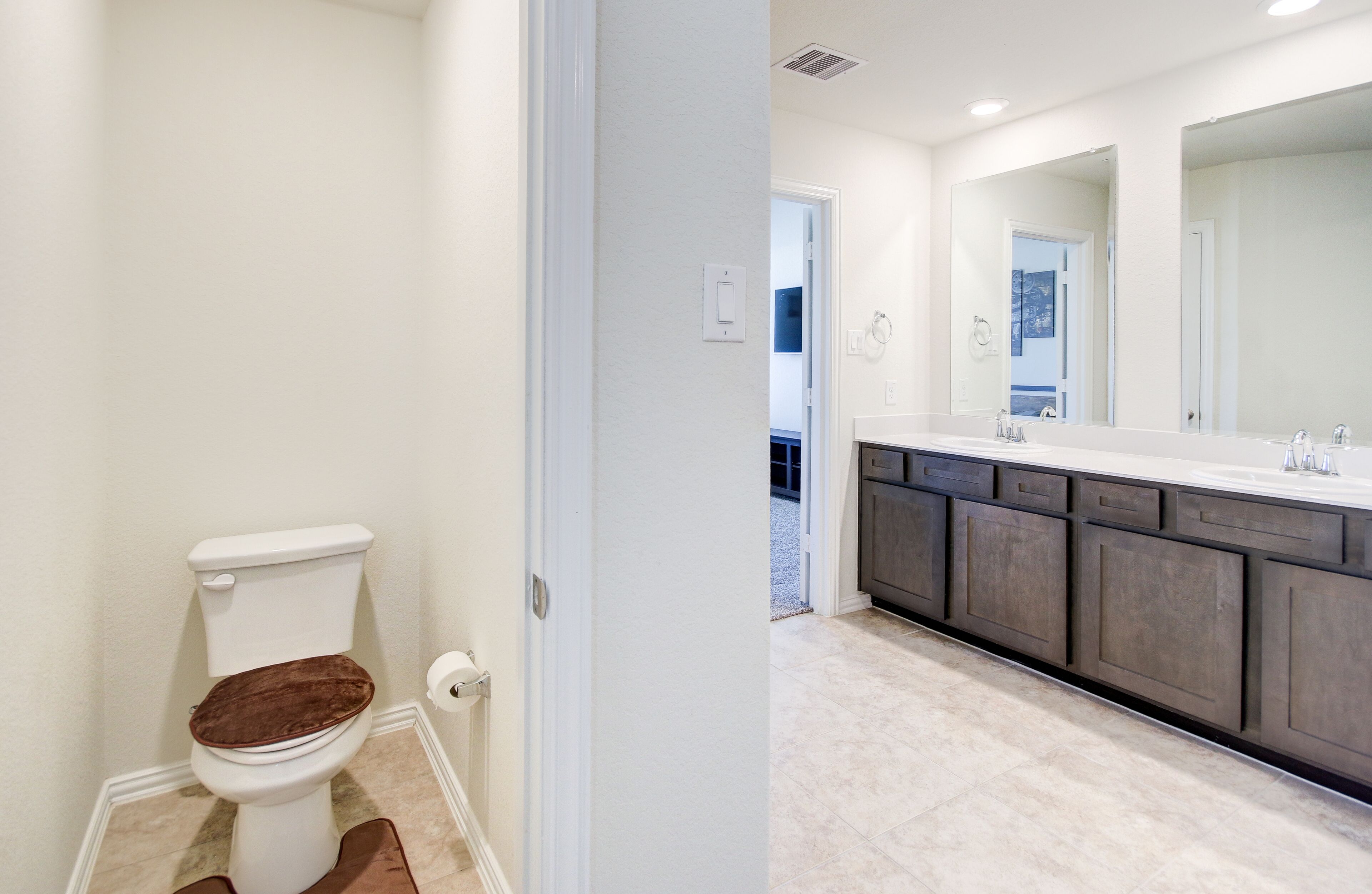 Un baño moderno con inodoro, lavamanos y un espejo grande.