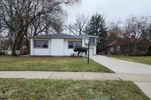 A single-story house with a front yard, a small tree, and a sidewalk.