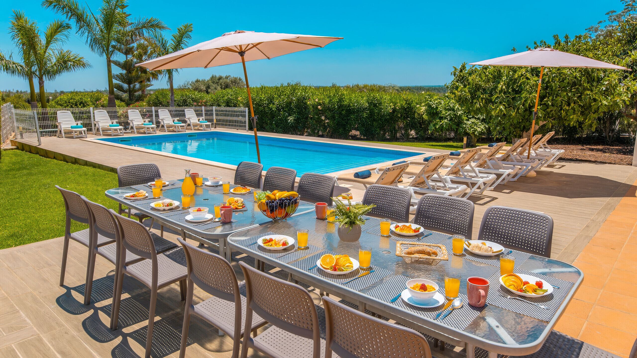 An outdoor dining area with a pool, lounge chairs, and umbrellas.