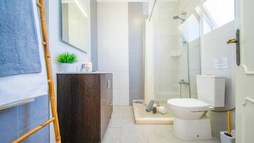 Une salle de bain moderne équipée d’une douche, de toilettes et d’un meuble-lavabo avec un miroir.