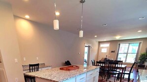 Una cocina moderna con una isla central, piso de madera e iluminación colgante.