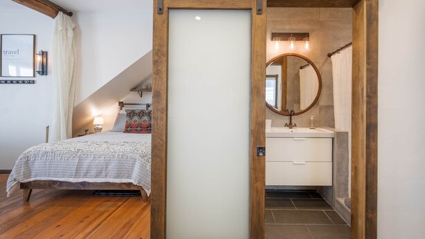 A bedroom with a bed, a nightstand, a framed picture, and a staircase leading to another room. - Pac. Street Studio: Style & space in heart of town (Telluride)