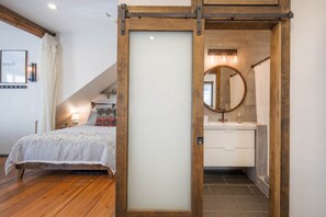 A bedroom with a bed, a nightstand, a lamp, and a wall-mounted picture.