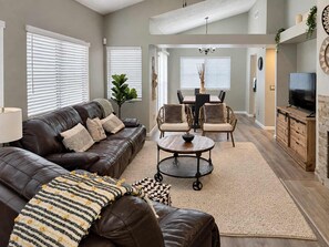 A living room with a leather sofa, a coffee table, and a TV stand. - Pet-Friendly 3BR | Fenced Yard | Community Pool (Chandler)
