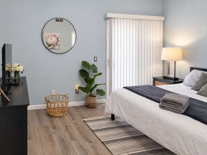 A modern bedroom with a bed, bedside table, lamp, and a large mirror on the wall. - Pet-Friendly 3BR | Fenced Yard | Community Pool (Chandler)
