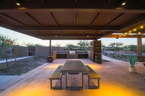 Eine Terrasse im Freien mit einem Holztisch und Bänken, einer Pergola darüber und Blick auf die umliegende Landschaft.