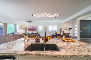Uma cozinha espaçosa com bancada de granito, pia embutida e luminária pendente.