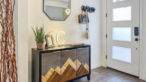 Un hall d’entrée moderne avec un meuble en bois foncé, un grand miroir et un élément décoratif mural.
