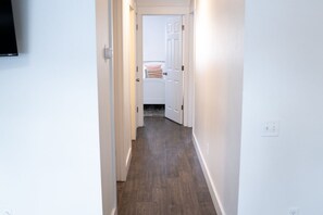Enter a modern hallway leading to a cozy space with a white door.