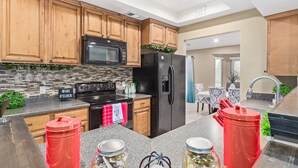 A modern kitchen with wooden cabinets, a black microwave, a stainless steel refrigerator, and a granite countertop. - Experience Deer Valley charm, just 14 mins from Grand Canyon University (Phoenix)