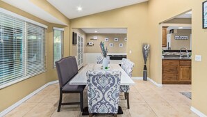 A dining area with a long table, chairs, and a kitchen in the background. - Experience Deer Valley charm, just 14 mins from Grand Canyon University (Phoenix)