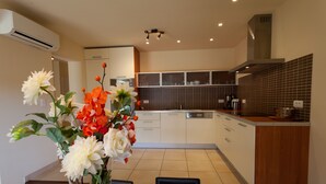 A modern kitchen with white cabinets, a wooden countertop, and a vase of flowers on the dining table.