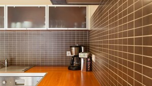 A modern kitchen with a black induction cooktop, a coffee maker, and a kettle on the counter.