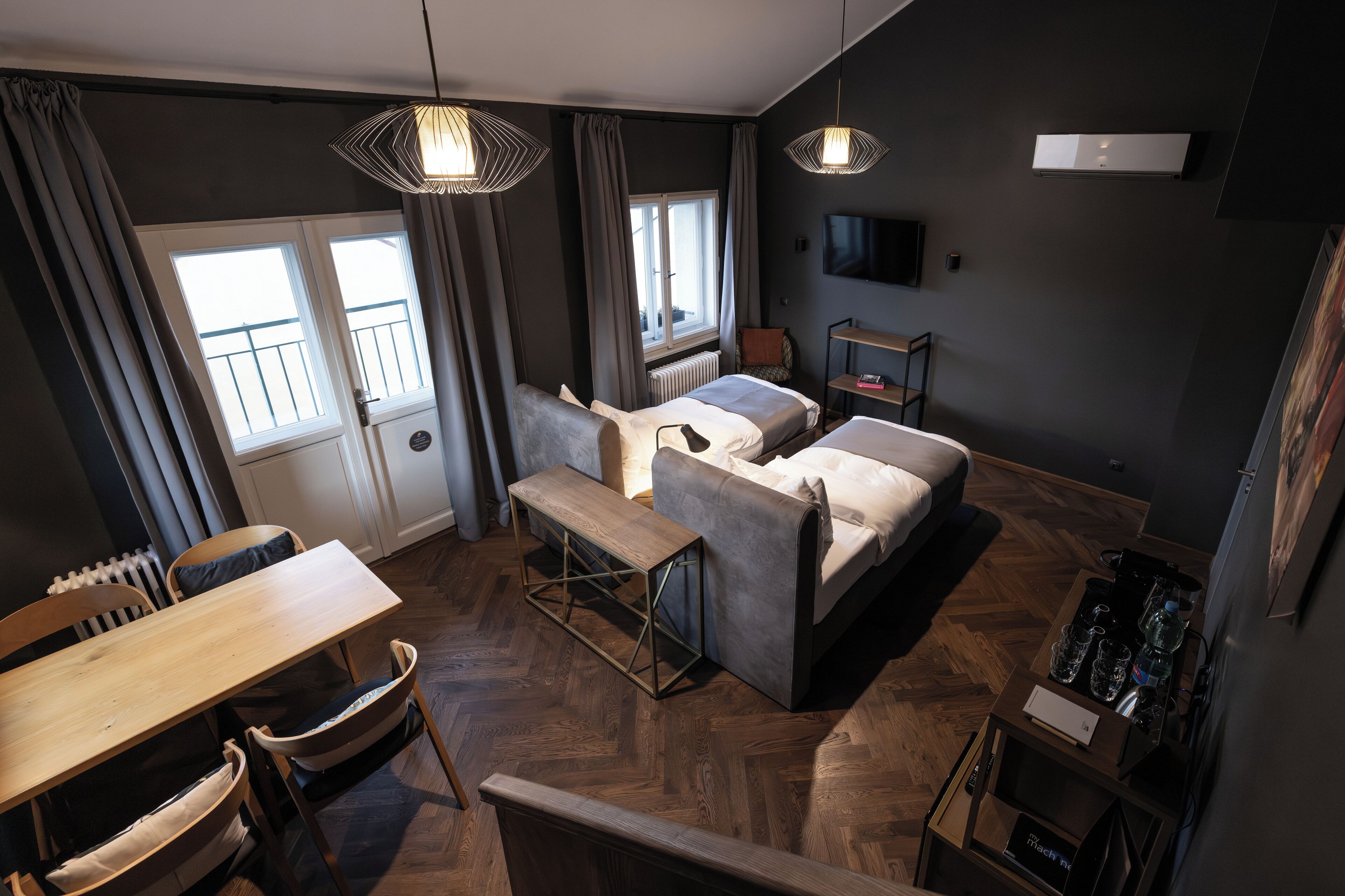 Ein modernes Wohnzimmer mit einer Couch, einem Esstisch und einer Bank. Es gibt ein Fenster mit Vorhängen, eine Heizung und einen an der Wand befestigten Fernseher.