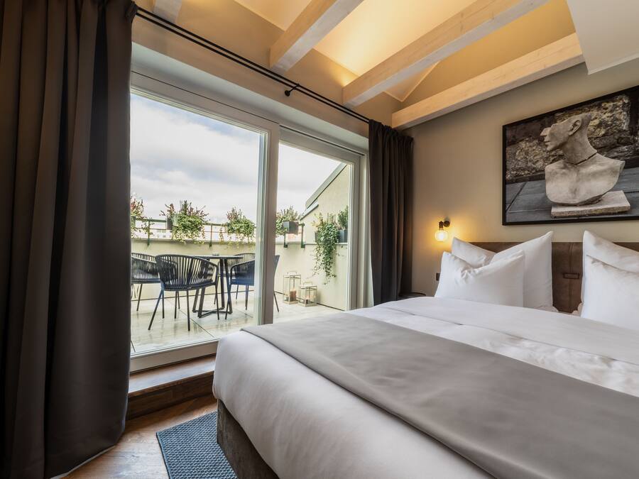 Un cuarto de hotel con una cama grande, vista al patio exterior y una escultura en la pared.