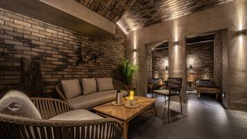 A cozy lounge area with a brick wall, a wooden coffee table, a sofa, and a chair.