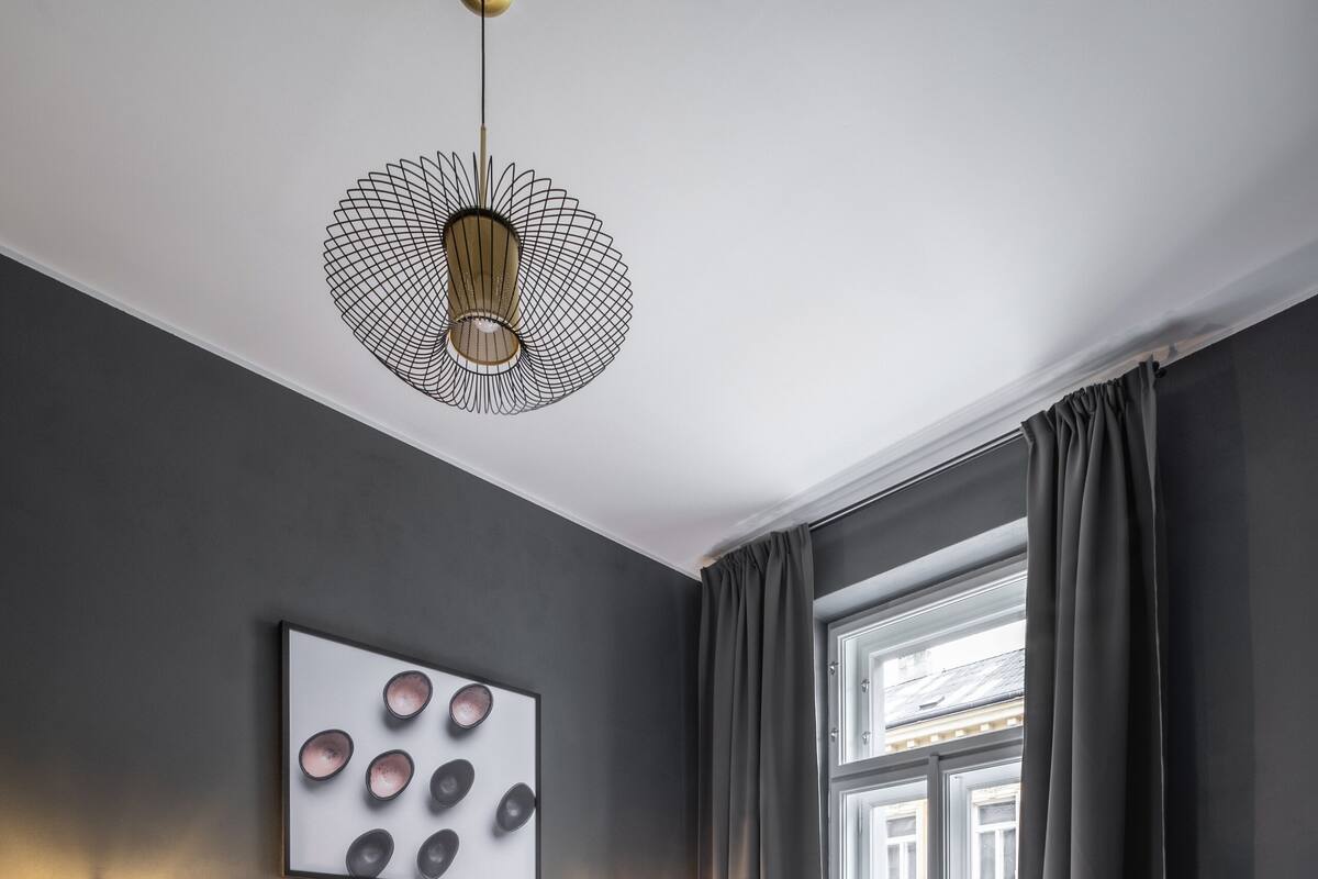 A modern bedroom with a large bed, a unique pendant light, and a view of the outside through a window.
