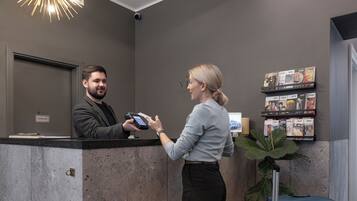 A reception desk with a modern chandelier, a digital display, and a wall-mounted photo display.