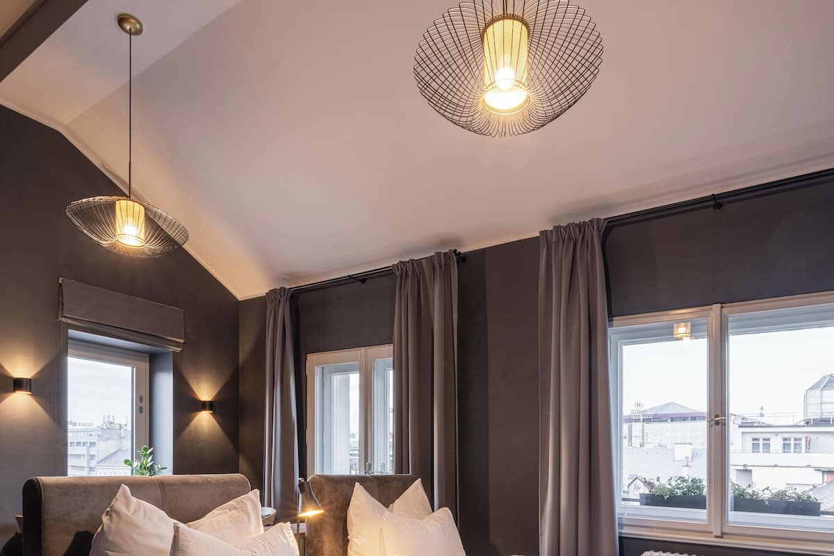 A modern hotel room with a large bed, two bedside tables, a window with curtains, and a view of the cityscape.