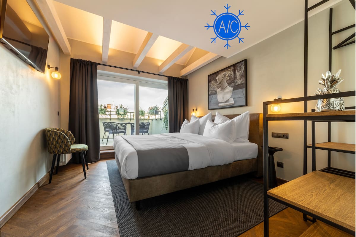 A modern hotel room with a large bed, a desk, and a view of the outdoors.