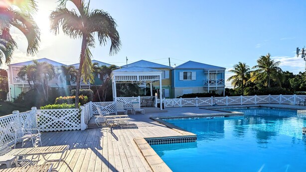 A wooden deck with lounge chairs and a pool.